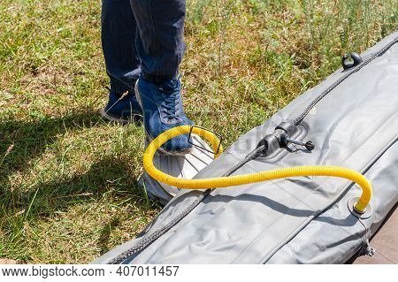 Inflatable Boat Pumping Process, Close-up. A Fisherman Pumps An Inflatable Boat With A Foot Pump.