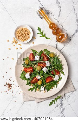 Healthy Vegetarian Salad With Fresh Arugula, Cherry Tomatoes, Soft Cheese, Olives And Pine Nuts