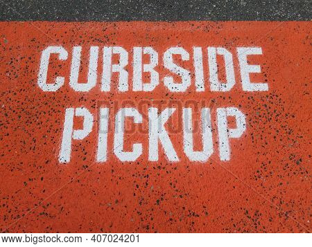 Orange Curbside Pickup Sign On Asphalt Or Ground
