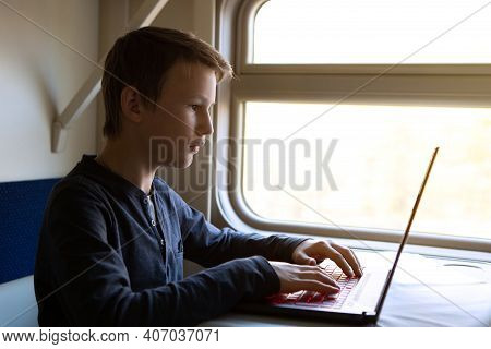 A Teenager In A Train Compartment At The Window Works In A Laptop. Modern Technologies. Russian Rail