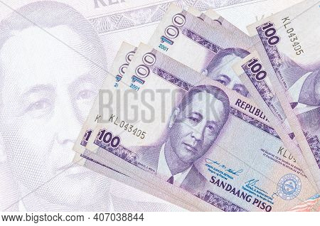100 Philippine Piso Bills Lies In Stack On Background Of Big Semi-transparent Banknote. Abstract Pre