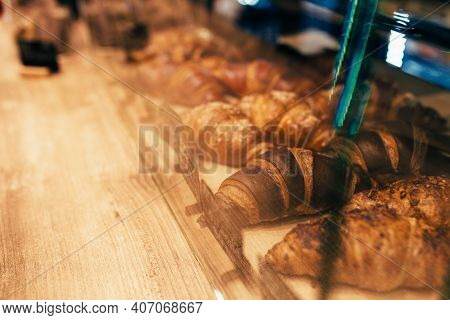 The Waiter Pulls Out Croissants In A Cafe Window. Blurred Background