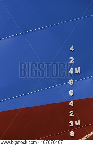 Draft Mark Numbers On Side Of Blue And Red Rust Proof Steel Hull Of Fishing Vessel In Vertical Frame