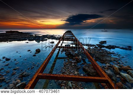 Serene Beach View in Mild Sunset Light. Long Rusty Leading Lines. Bridge Support goes into the Distance of the Sea. Batroun. Lebanon.