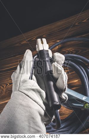 The Welder In White Welding Leather Gloves Holds A Wire With An Electrode Holder In His Hand. Studio