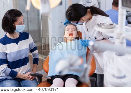 Dentist Using Modern Dental Equipment For Little Girl Treatment In Clincic. Dentistry Specialist Dur