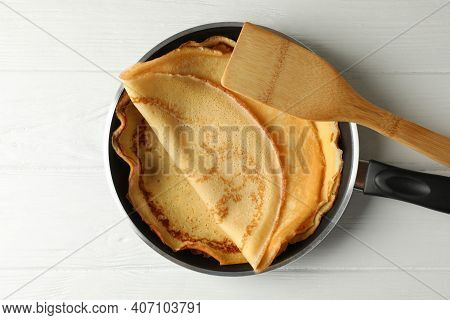 Pan With Tasty Thin Pancakes And Spatula On Wooden Table