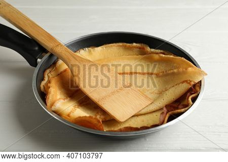 Pan With Tasty Thin Pancakes And Spatula On Wooden Table