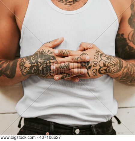 Tattooed man clasping his hands on his stomach while lying on the floor. 2 OCTOBER 2020 - CHIPPENHAM, UK