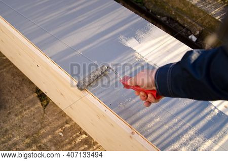 Close Up Of Painter Arm Painting A Wall With Paint Roller, Wood Wardrope Is Painted By Grey Color Pa