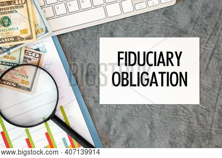 Fiduciary Obligation Is Written In A Document On The Office Desk With Office Accessories, Money, Dia
