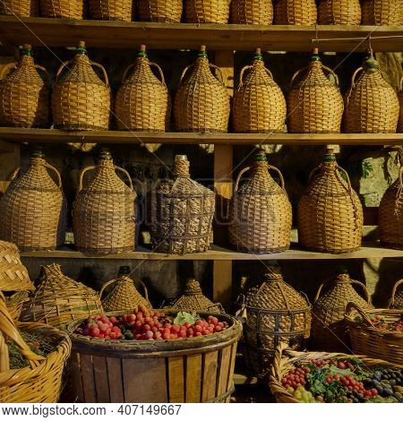 Wine bottles on shelves and baskets with grapes in wine-cellar