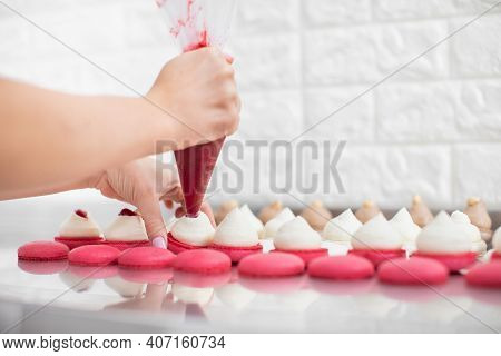 Filling Macarons With Ganache Cream And Fruit Jam. Close Up Cropped Shot Of Hands Of Female Confecti