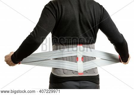 A Man Puts On An Orthopedic Corset, Standing With His Back To The Camera. Man In A Supportive Corset