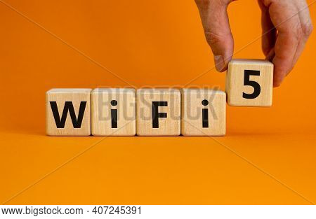 Wifi 5 Symbol. Businessman Holds A Wooden Cube With Words Wifi 5. Beautiful Orange Background, Copy 