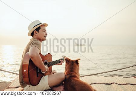 A Man Wear Straw Hat And Playing Guitar Music Song Near The Sea Sunset With A Dog Pet.
Travel, Vocat
