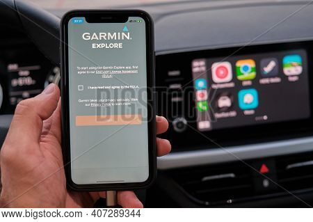 Garmin Explore Logo On The Screen Of Smart Phone In Mans Hand On The Background Of Car Dashboard Scr