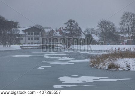Snowstorm At The Mill Pond In Oliwa. Old Mill In The Background. Gdansk, Oliwa, Poland.