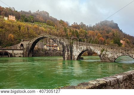 Cold green waters of the Sercchio River. Italy. Province of Tuscany. The vicinity of the city of Lucca, Ponte della Maddalena Bridge. Bridge built a thousand years ago. Cold windy winter day