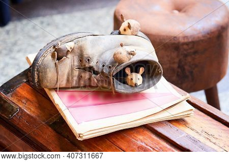 Close-up Mice And Brown Shoes On Wooden Chest. Mouse Sleeping In Old Torn Brown Shoe. Figurines In S