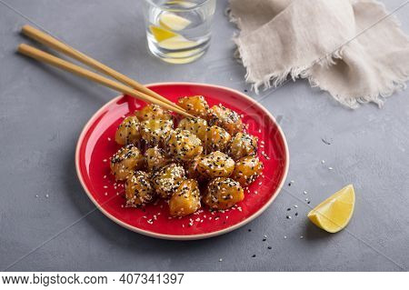 Traditional сhinese Fried Apples In Caramel With Sesame Seeds On Red Vintage Plate With Chopsticks O