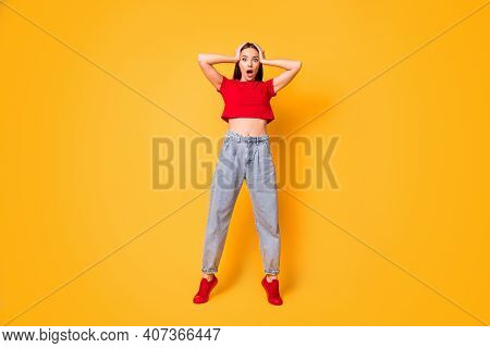 Full Size Photo Of Shocked Lady Hands On Head Stand On Toes Wear Red Crop Top Jeans Shoes Isolated O