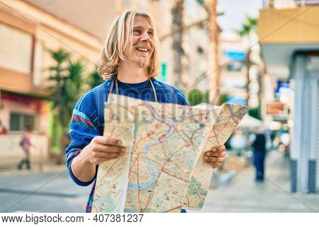 Young scandinavian tourist man smiling happy using map at the city.