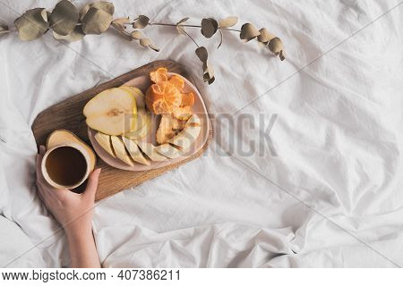Having A Breakfast In Bed From A Tray With Fruits And Tea In White Clean Bed. Mindful And Quiet Livi