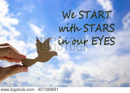 Man Hand Holding Wooden Bird On Cloud Sky Background. Words 'we Start With Stars In Our Yeys'. The D