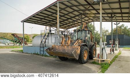 Yellow Tractor On Gas Station. Refill. Heavy Equipment. Tanks With Fuel.