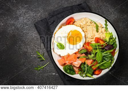 Savory Breakfast. Oatmeal Porrige With Salted Salmon, Egg And Fresh Salad. Top View On Black Table.
