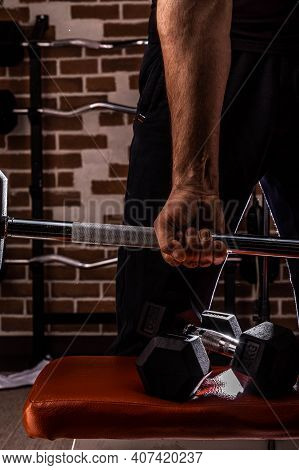 Female Personal Trainer Helping A Young Man Lift Dumbells While Working Out In A Gym