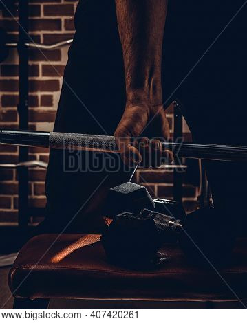 Female Personal Trainer Helping A Young Man Lift Dumbells While Working Out In A Gym