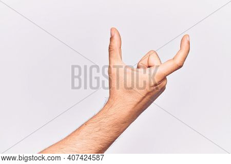 Close up of hand of young caucasian man over isolated background picking and taking invisible thing, holding object with fingers showing space 