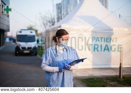 Female Key Doctor Checking Patient Report Form Medical Card,standing Outside Clinic Exterior Triage 