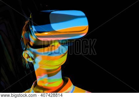 Woman Using Virtual Reality Headset And Looking Around At Interactive Technology Exhibition With Col