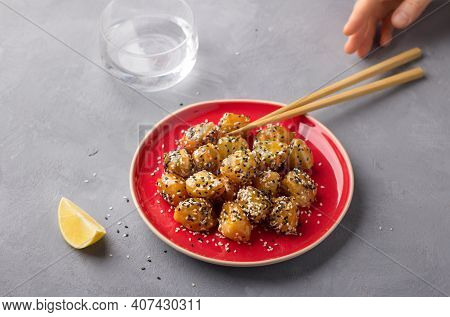 Traditional сhinese Fried Apples In Caramel With Sesame Seeds On Red Vintage Plate With Chopsticks O
