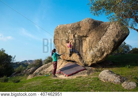 Two Young Girls Climb Bouldering Outdoors. Rock Climber Climbs A Difficult Route. Do Sports Outside 