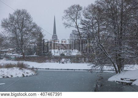 Gdansk, Oliwa, Poland - 16 January 2021: Snowstorm At The Mill Pond In Oliwa. Church Tower In The Ba