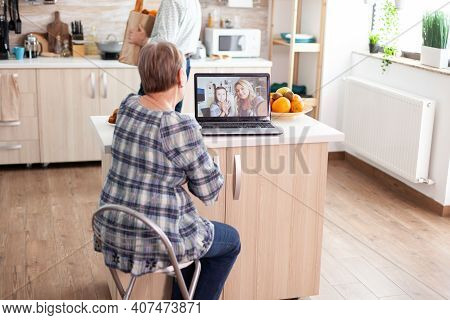 Enthusiastic Senior Woman Talking With Family Online Using Laptop Webcam During A Video Conference S