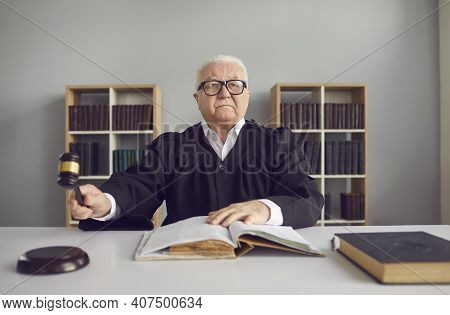 Senior Man Professional Judge Sitting In Conference Hall During Trial And Striking With Hammer