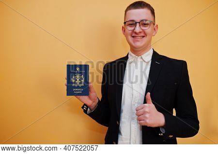 Young Handsome Man Holding Jamaica Passport Id Over Yellow Background, Happy And Show Thumb Up. Trav