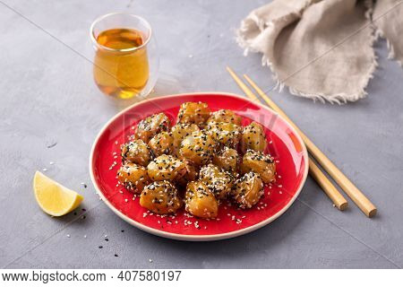 Traditional сhinese Fried Apples In Caramel With Sesame Seeds On Red Vintage Plate With Chopsticks W