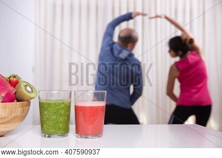 Green Smoothie With Focused Kiwis And Woman Exercising On Unfocused Background