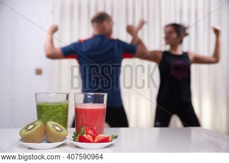 Green Smoothie With Focused Kiwis And Woman Exercising On Unfocused Background