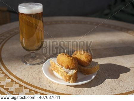 Spanish Pinchos Of Croquettes Close To Glass Of Beer. Pincho Served Over Sunny Terrace Table