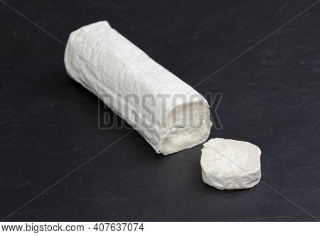Goat Cheese Roller With Slice. Isolated Over Black Slate