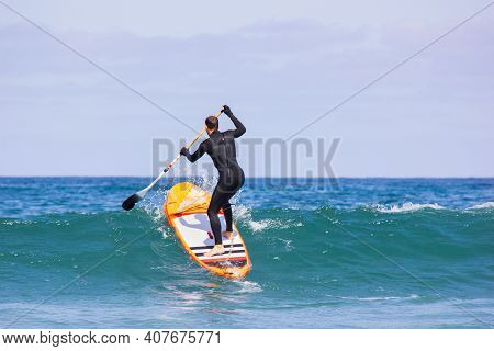 Man Surfing On Inflatable Stand-up Paddle Board At Summer Sunny Day. Extreme Sport Activity. Surfer 