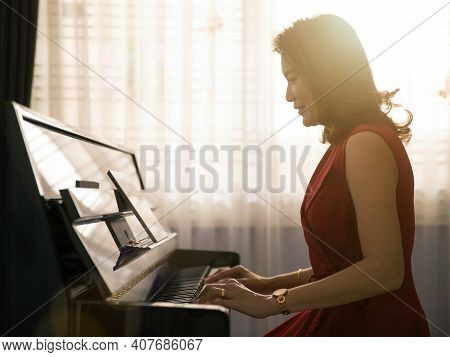 Middle Age Dignified Asian Woman Learning And Studying New Skills How To Play The Piano Via Online C