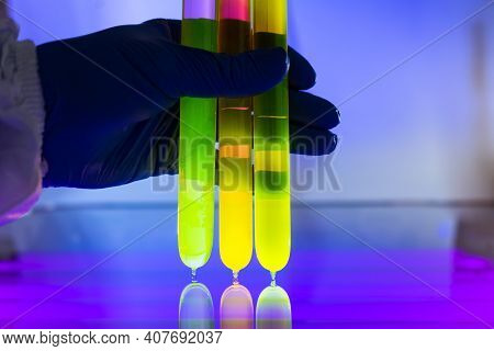 Fluorescein Glowing In Flask Under Ultraviolet Light. A Closeup Of Man Hand Holding Up A Vial  Fluor